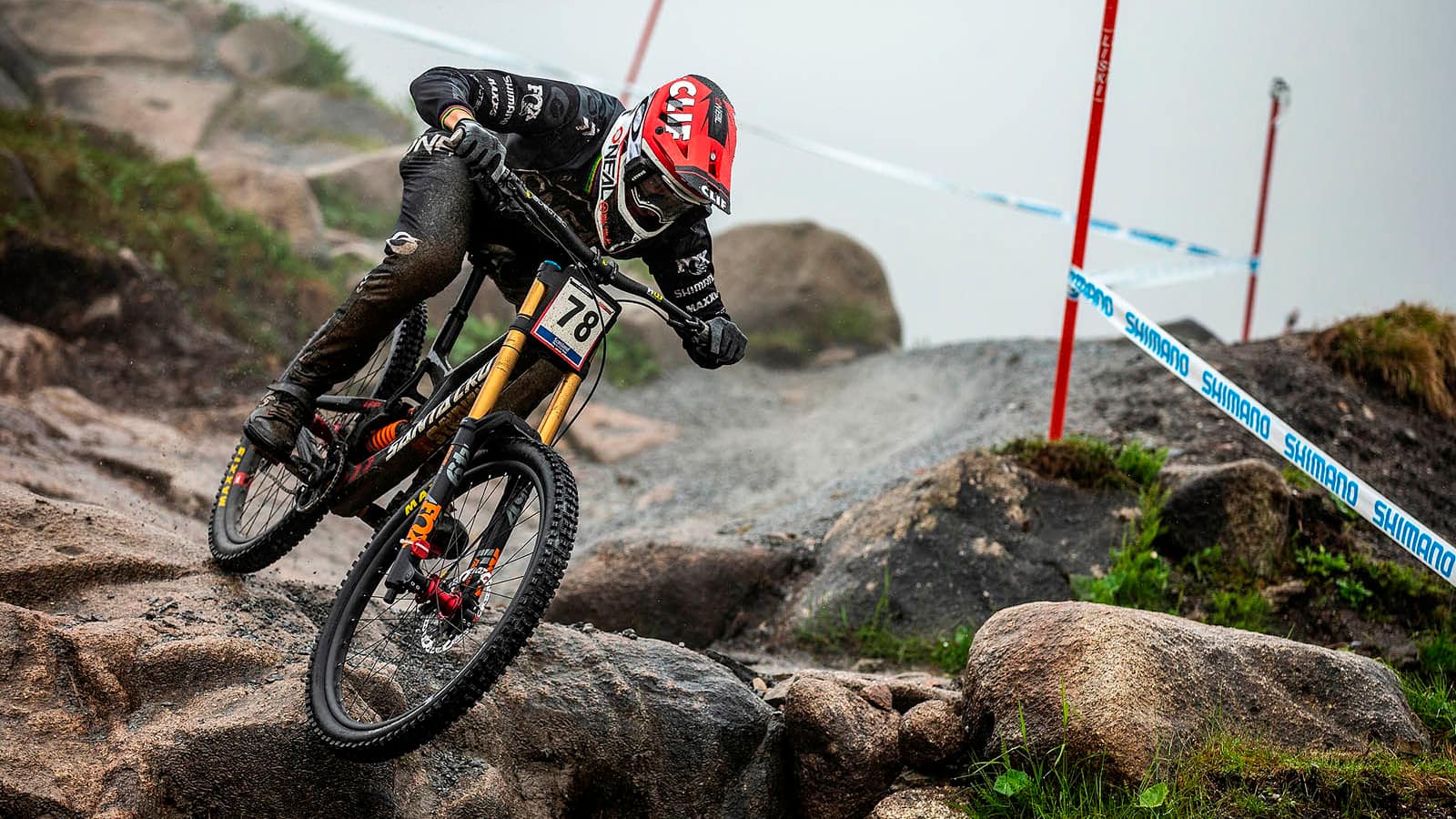 a biker in a red helmet going downhill on a yellow mountain bike