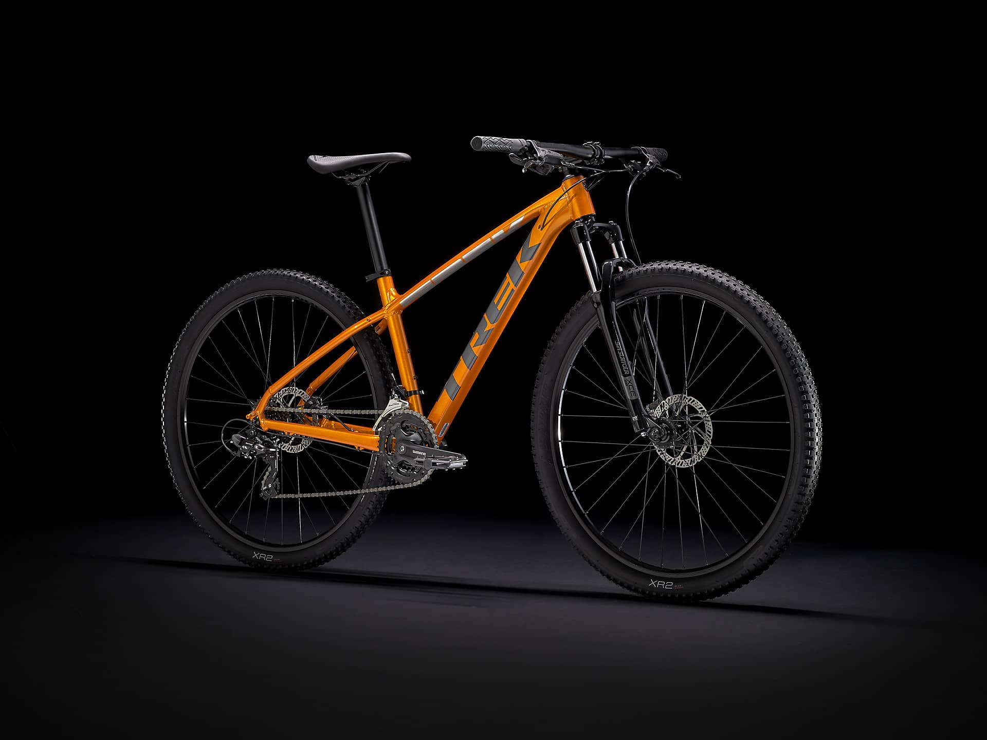 a mustard colored mountain bike with black tires on a black background